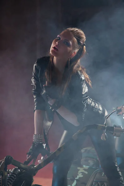 Schöne Fotomodel in Lederkleidung und posiert mit einzigartigen Fahrrad in der Nacht — Stockfoto