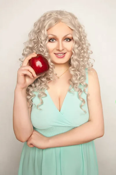 Pretty smiling young woman standing with big red apple on white background isolated — Stock Photo, Image