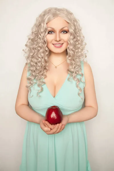Docela s úsměvem mladá žena stojící s velké červené jablko na bílém pozadí, samostatný — Stock fotografie