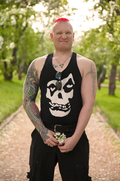 alternative tattoo rehead man walking on the apple tree park with flowers