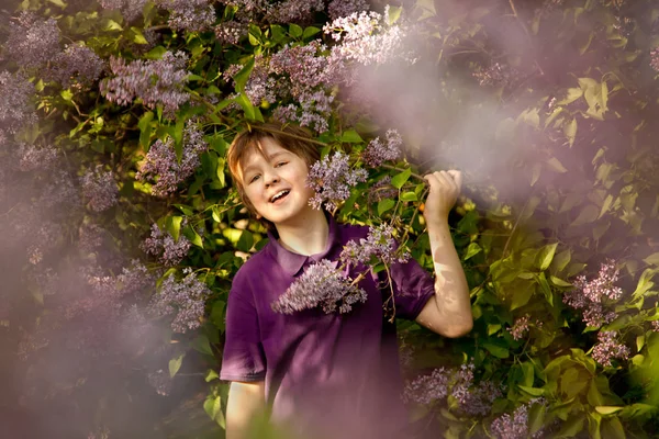 Joli garçon gentil souriant dans les lilas dans le jardin d'été — Photo