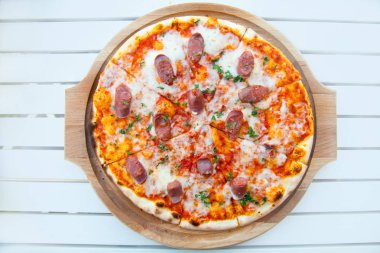 Beyaz ahşap masa üstü görünümü üzerinde peynir ve sığır sosis ile lezzetli sıcak pizza