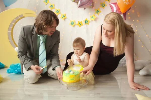 little baby birthday one year girl crushing her yellow cake wth mother and father