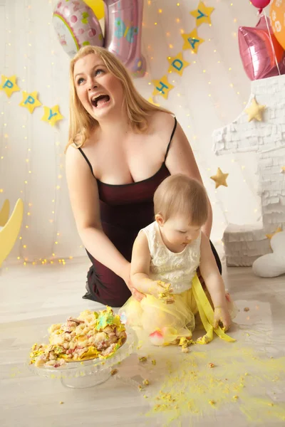 little baby birthday one year girl crushing her yellow cake wth mother and father