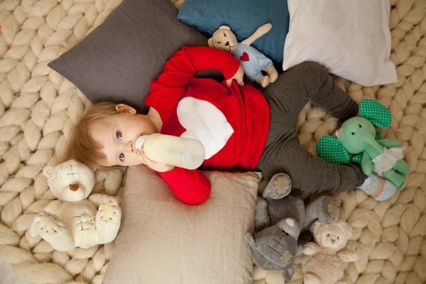 Kleine baby eten de fles melk liggend op de enorme gebreid plaid alleen bovenaanzicht — Stockfoto