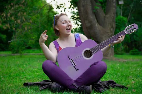 Красивая женщина с черной гитарой в парке — стоковое фото