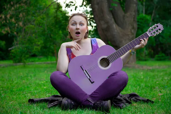 Mulher bonita com guitarra preta no parque — Fotografia de Stock