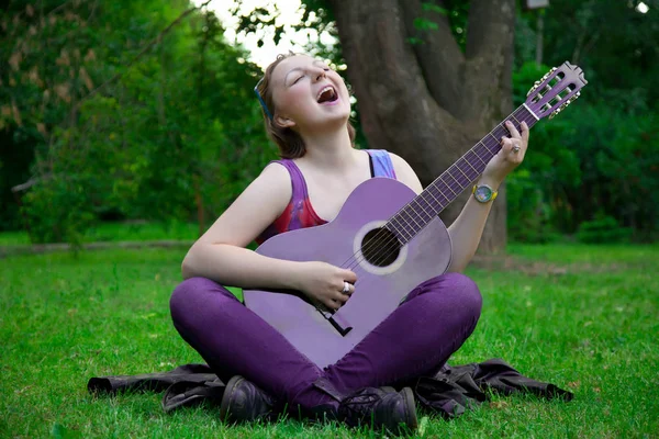 Pretty woman with black guitar in the park — Stock Photo, Image