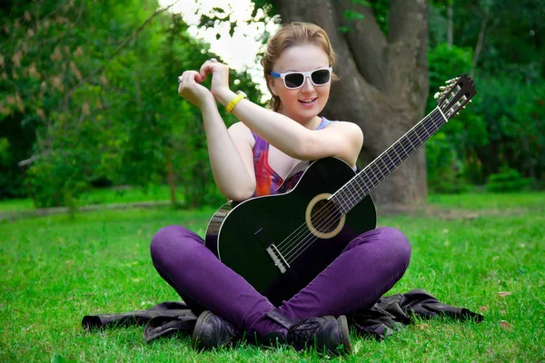 Mulher bonita com guitarra preta no parque — Fotografia de Stock