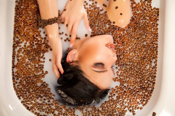 Beautiful woman in the milk bath with coffee beans — Stock Photo, Image