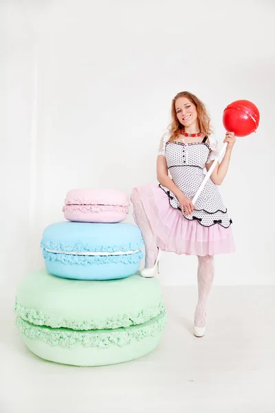 Mooie jonge dame in polka dot pin up jurk met gigantische snoep in witte achtergrond studio — Stockfoto