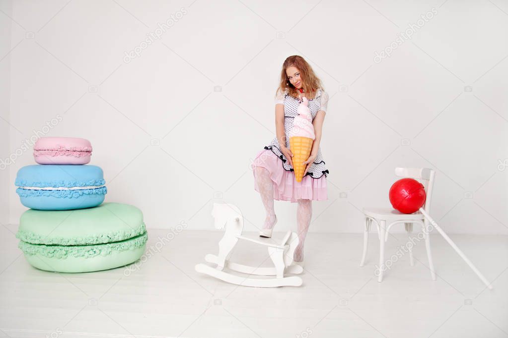 pretty young lady in polka dot pin up dress with giant sweets in white background studio