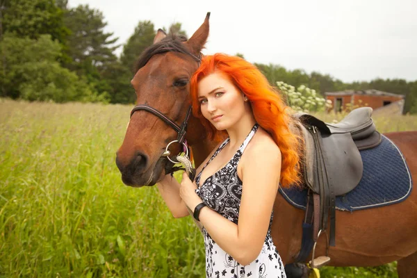 Oranje haar vrouw en haar bruin paard in het veld gewoon ontspannen in de zomerdag — Stockfoto