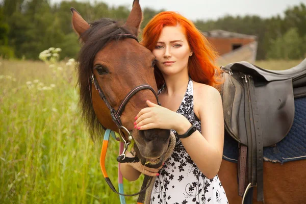 Oranje haar vrouw en haar bruin paard in het veld gewoon ontspannen in de zomerdag — Stockfoto