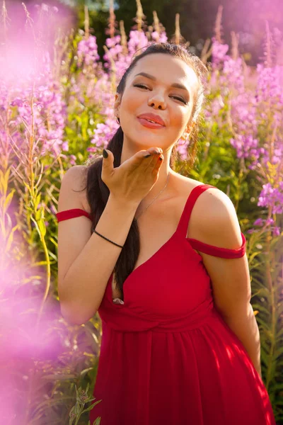 Αρκετά ευτυχής χαμογελαστοί μελαχρινή γυναίκα σχετικά με τη φύση στο πεδίο ροζ μοβ λουλούδια — Φωτογραφία Αρχείου