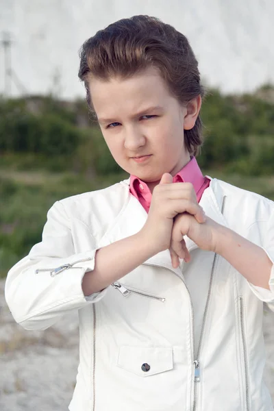 Cool witte kleding mode kind jongen met onbeleefd brutale gezicht buiten in de buurt van grote berg — Stockfoto