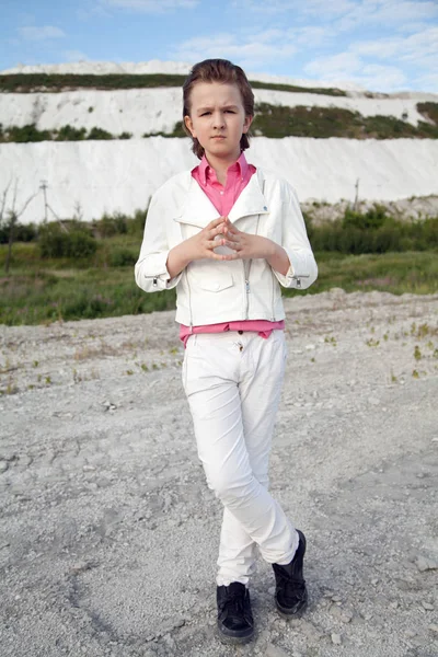 Cool witte kleding mode kind jongen met onbeleefd brutale gezicht buiten in de buurt van grote berg — Stockfoto