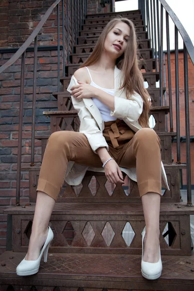 Menina bonita vestindo casaco branco e calças bege andando na rua — Fotografia de Stock