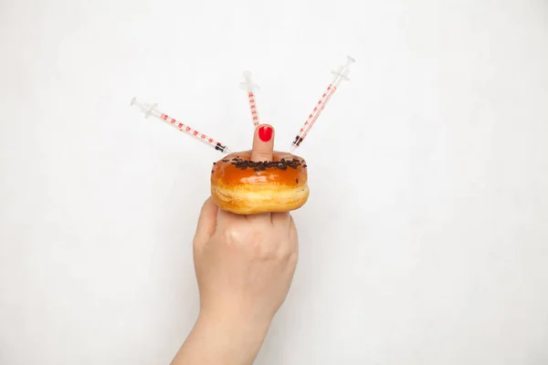 Ближе к врачу женщина делает инъекции с помощью шприца от диабета в пончик — стоковое фото