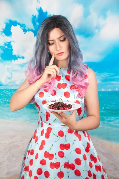 Vrolijke jonge pin-up girl eten van zoete kers staan — Stockfoto