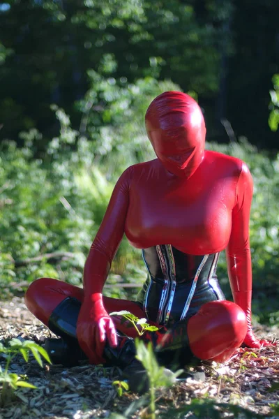 Kurvige Alien-Frau trägt roten schwarzen Latex-Catsuit, enges Korsett und Maske auf der Straße — Stockfoto