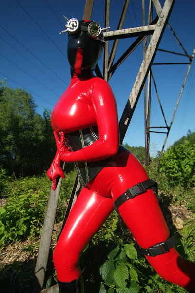 Curvy donna aliena indossa tuta in lattice nero rosso, corsetto stretto e maschera per strada — Foto Stock