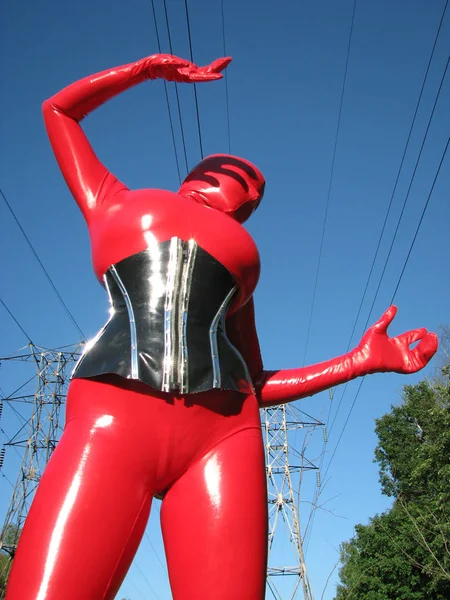 Mulher alienígena curvilínea vestindo terno de látex preto vermelho, espartilho apertado e máscara na rua — Fotografia de Stock