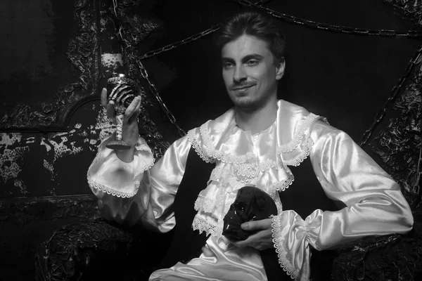 handsome historical man wearing medieval costume and sitting on the gothic throne alone