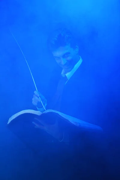 Красивый мистический писатель, стоящий на черном фоне в дыму — стоковое фото