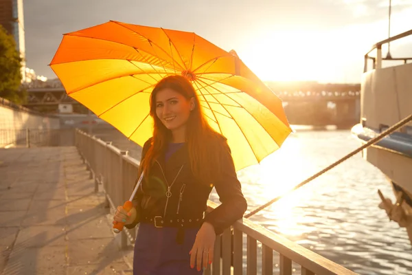 Красивая молодая рыжая женщина с оранжевым большим зонтиком на городской улице — стоковое фото
