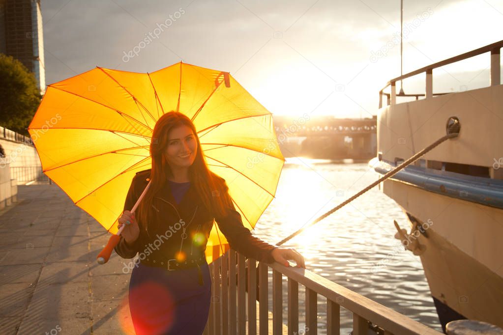pretty young redhead woman with orange big heart umbrella on the city street