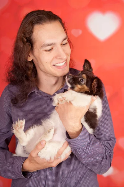 Przystojny, uśmiechający się zadowolony człowiek z 3 miesięcy Brodawka mały szczeniak. chłopiec i pies są przyjaciele. — Zdjęcie stockowe