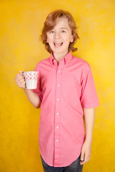 Joven guapo con taza de bebida caliente sobre fondo amarillo brillante estudio —  Fotos de Stock