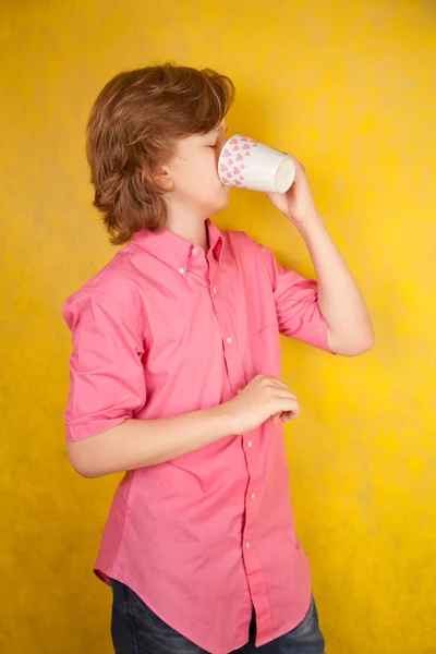 Bell'uomo giovane con tazza di bevanda calda su sfondo giallo studio luminoso — Foto Stock