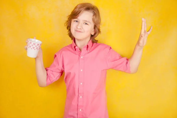 Knappe jongeman met kop warme drank op gele heldere studio achtergrond — Stockfoto