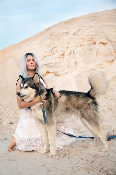 Bela jovem dona e sua linda feliz malamute cão na pedreira deserto areia branca — Fotografia de Stock