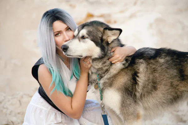 Hermosa joven propietaria y su encantador perro feliz malamute en la cantera del desierto de arena blanca — Foto de Stock