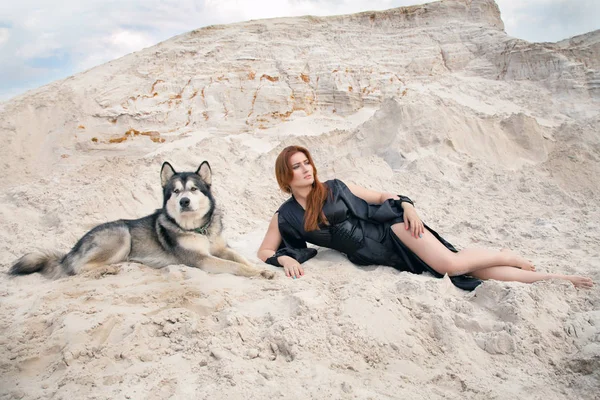 Właściciel piękną młodą kobietę i jej piękny szczęśliwy pies Malamut na pustyni kamieniołom biały piasek — Zdjęcie stockowe