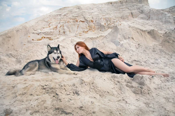 güzel genç kadın sahibi ve onun güzel mutlu köpek malamute çölde beyaz kum ocağı