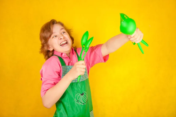 Αστείος αγόρι παιδί φοράει ροζ πουκάμισο και πράσινη ποδιά στο κίτρινο φόντο. κουζίνα αγώνα. — Φωτογραφία Αρχείου