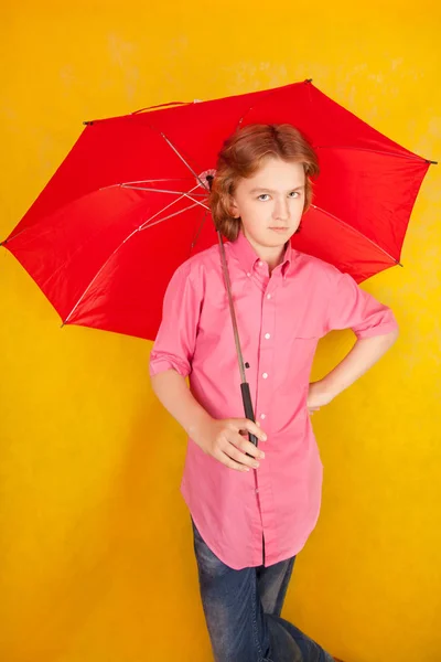 Mignon enfant avec parapluie lumineux rouge sur fond jaune seul — Photo