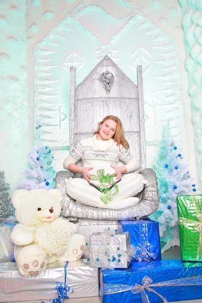 Αρκετά ευχαριστημένος έγκυος γυναίκα φοράει το λευκό πουλόβερ και κάθεται στην καρέκλα Χριστούγεννα με τα Χριστούγεννα και το νέο έτος δώρο κουτιά — Φωτογραφία Αρχείου