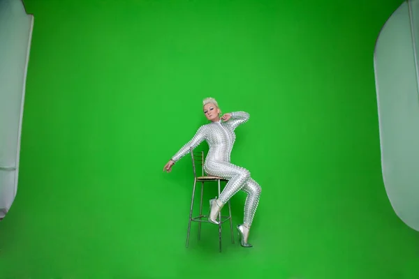 Strana bella donna futuristico seduto sullo sfondo verde cromakey da solo — Foto Stock