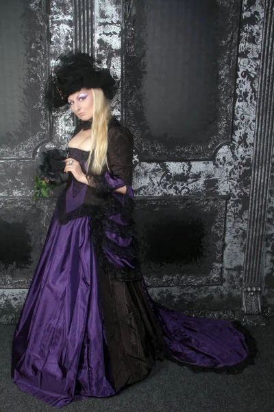 Pretty blonde woman wearing historical purple black long dress — Stock Photo, Image