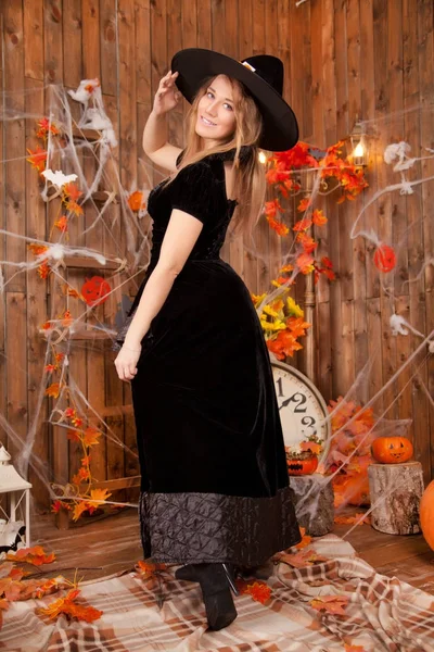 아름 다운 클래식 검은 마법사 벨벳 드레스를 입고 여 자가 마녀와 모자, 오렌지 악마 할로윈 호박과 거미줄을 지적 — 스톡 사진