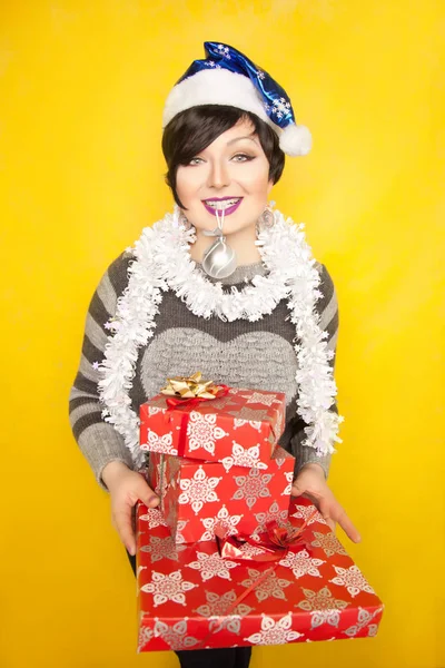 Pretty short hair brunette woman wearing cute sweater and standing alone with holiday gifts in the studio — Stock Photo, Image