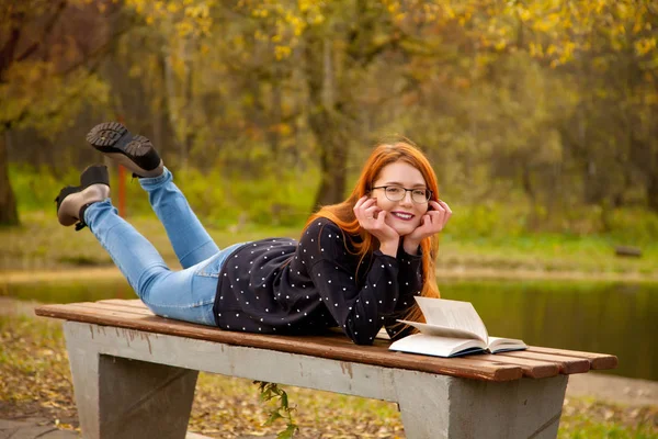 혼자 공원에서 책을 함께 포즈를 취하는 귀여운 스웨터 입고 예쁜 빨간 머리 소녀 — 스톡 사진