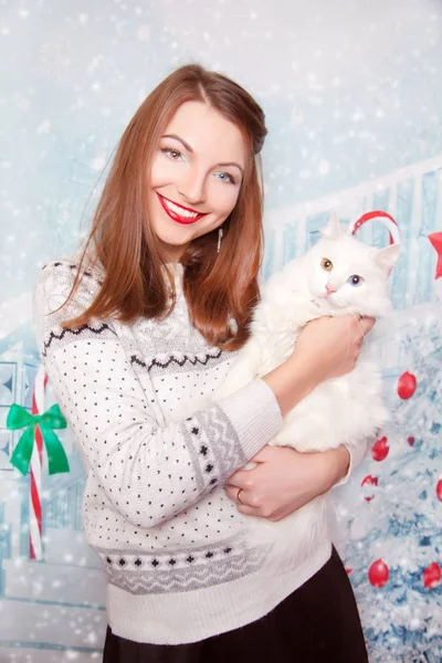 Muito bonito jovem menina vestindo camisola branca de Natal e de pé com gato doméstico sozinho no fundo do estúdio de ano novo — Fotografia de Stock