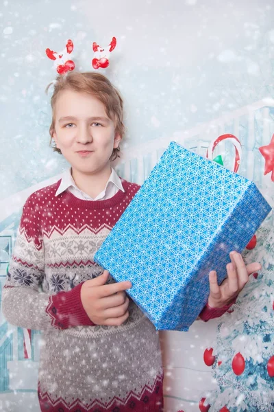 Lycklig unge pojken bär jul tröja och stående med blå presentask — Stockfoto