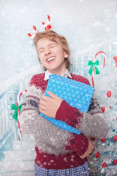 Menino feliz jovem sorrindo e rindo com presentes de Natal de Ano Novo — Fotografia de Stock